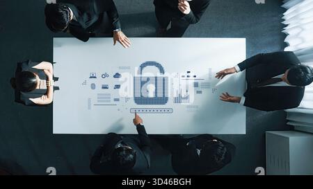 A business team collaborates around a table, focusing on cybersecurity strategies illustrated by digital graphics of a lock, emphasizing data Stock Photo
