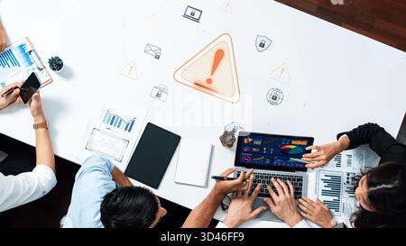A business team actively collaborates in a modern office, analyzing data and discussing risk management with a laptop and various charts displayed on Stock Photo
