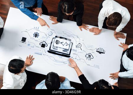 A diverse group of professionals engages in a collaborative technology design session, emphasizing coding symbols and innovative ideas on a digital Stock Photo