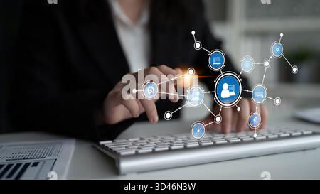 A business professional interacts with a keyboard in a modern workspace, showcasing digital connection icons that symbolize networking and Stock Photo