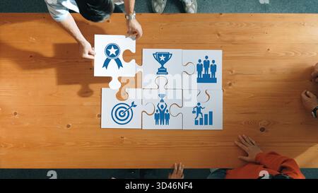 Aerial view of hands working together on puzzle pieces, illustrating themes of achievement, strategy, and teamwork in a collaborative business Stock Photo