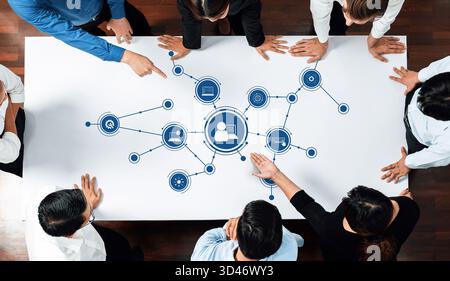 Team of diverse professionals engaging in discussion and collaboration around a table showcasing technology integration and connectivity in a modern Stock Photo