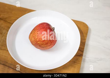 Red Apple in a white plate. Malus domestica, Fresh and healthy fruit. Stock Photo
