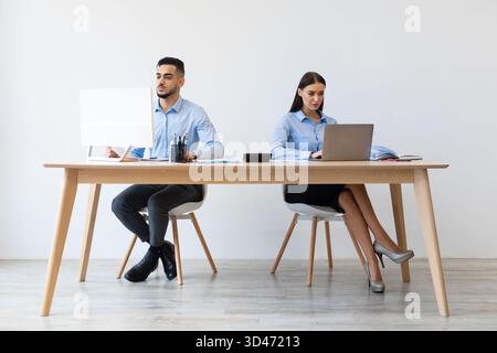 Focused Colleagues Collaborate in a Modern Office Setting While Using Laptops Stock Photo