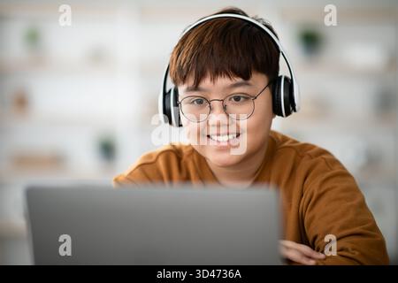 Cheerful Boy Engaged in Online Lesson Using Laptop and Wireless Headset Stock Photo