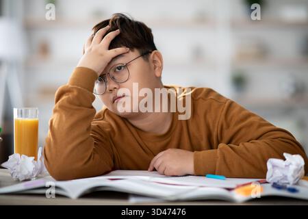 Cute Asian Schooler Daydreaming While Studying at Home During Homework Sessions Stock Photo