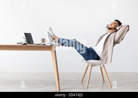 Relaxed Man Enjoying Lounge Music After Work at His Home Desk on a Peaceful Evening Stock Photo
