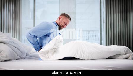 Young Man Working Overtime At Office, Suffering From Severe Headache. Stock Photo