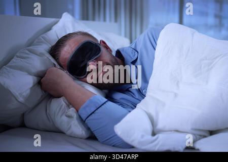 Dreamy Nap Time: Young Businessman Rests With Eye Mask On. Stock Photo