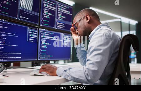 Sad Programmer Navigates Maze Of Broken Code At Business Desk. Stock Photo