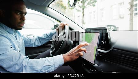 Man Navigating With GPS Map On Car Dashboard As Auto Navigator. Young African Male Tracking Speedometer Using GPS Map Stock Photo