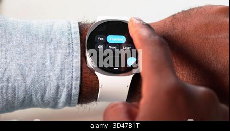 African-American Man Engaged In Messaging On Smartwatch, Tech Professional Stock Photo
