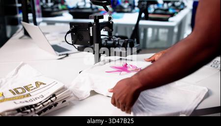 Young Black Man Operating Custom Digital Print T-shirt Cloth Heat Press Machine For Sale. Stock Photo