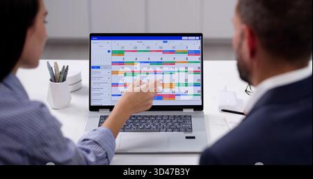 Busy Professionals Planning Meeting Using Online Calendar On Laptop Screen. Stock Photo