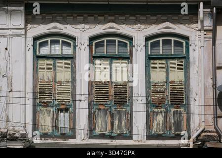 Symmetrical close-up of three arched colonial windows on a historic shophouse facade in George Town, Penang, Malaysia, a UNESCO World Heritage Site. Stock Photo