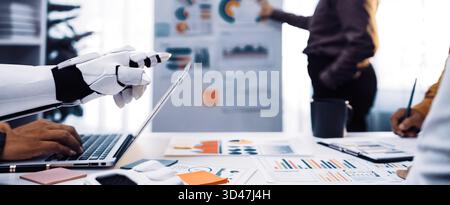 A modern office scene showcasing a robot assistant collaborating with a human team in a business meeting. Team members analyze data presented on Stock Photo