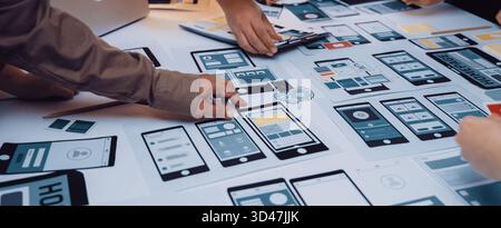 A diverse group of professionals collaborates on mobile application design, actively engaged in creating user interface layouts and sharing innovative Stock Photo