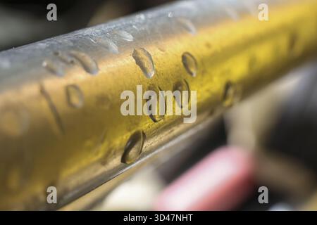 Detailed macro close up of brass metal surface with clear water droplet formation. golden texture shows condensation creating calm and focused abstrac Stock Photo