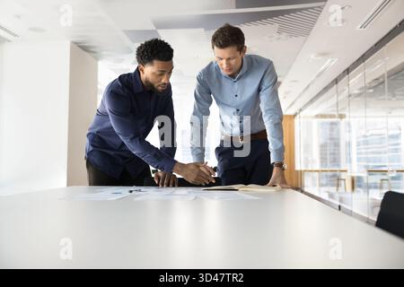 Two gen z workmates of diverse ethnicity collaborating at workplace Stock Photo