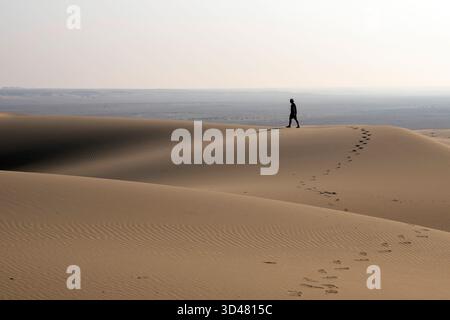 Doha, Qatar - October 30, 2025: man walking in the desert. Singing dune Qatar Stock Photo