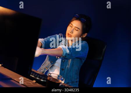 Young beautiful Asian businesswoman taking break with stretching body with ache symptom for relaxing muscle after finishing overworked load report at Stock Photo