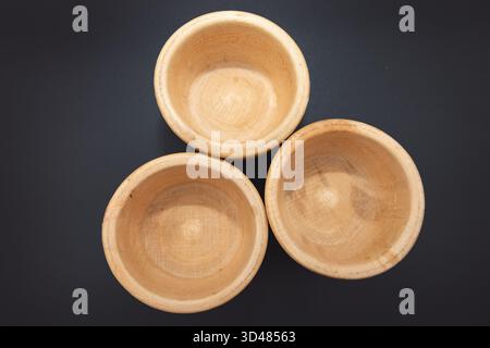 Three small wooden bowls on dark background for kitchen and cooking use Stock Photo