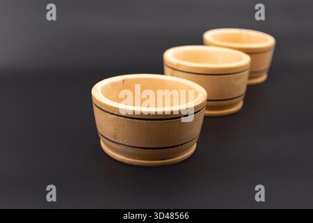 Three small wooden bowls on dark background for kitchen and cooking use Stock Photo