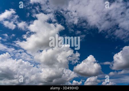 White cumulus clouds against a deep blue sky Stock Photo