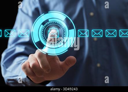 Hand selecting an email icon on a glowing digital interface, representing modern communication and futuristic technology Stock Photo