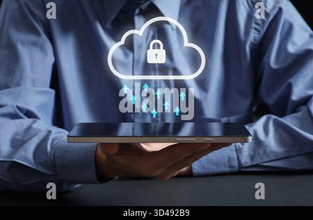 Person holding a tablet displaying a secured cloud icon with arrows symbolizing data upload, representing secure cloud computing Stock Photo