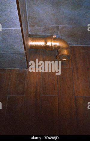 Toilet drain pipe painted in gold color, analog film photo with raw texture, warm tones, and quirky everyday aesthetic. Stock Photo
