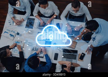 A diverse team collaborates on cloud security solutions within a modern office setting, utilizing laptops and engaging in innovative data sharing and Stock Photo