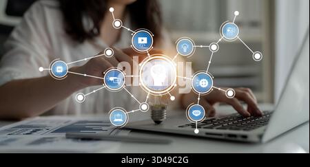 This image illustrates a captivating concept of creativity and technology, featuring a light bulb connected to digital icons in a business environment Stock Photo