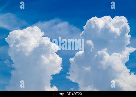 Upward view of fluffy white clouds drifting across a bright blue summer sky in Tamsui, New Taipei, Taiwan. Stock Photo