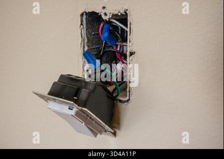 Closeup of a retrofit smart lighting dimmer being installed in a wall junction box. Modern home automation technology upgrade showing wiring, tools, a Stock Photo