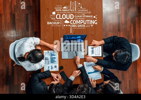 A diverse team meets around a conference table to discuss cloud computing strategies using data analytics, showcasing modern technology and Stock Photo
