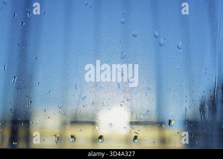 Condensation forming on double glazed window. Contrast cold air and humidity. Drops on glass. Cold room. Backlight poor glass sealing Stock Photo