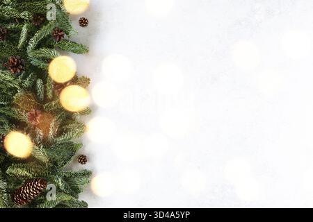 Christmas background or a card with fir branches, pine cones and bokeh lights on a white background. Merry Christmas and Happy New Year! Stock Photo