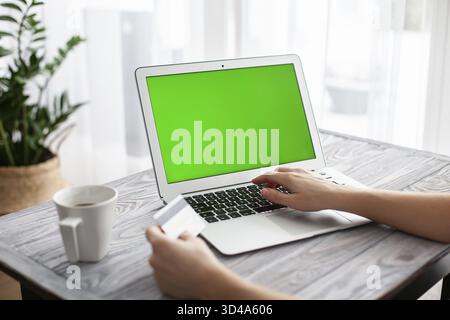 Woman shopping online using laptop with green screen and a credit card Stock Photo