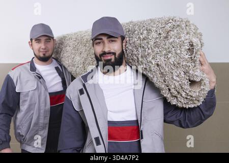 Happy male carrying a carpet in new home Stock Photo