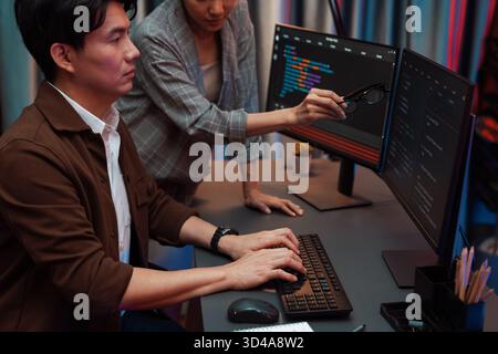 IT developers discussing with point to intelligent website development coder system running data online two screens information technology at neon Stock Photo