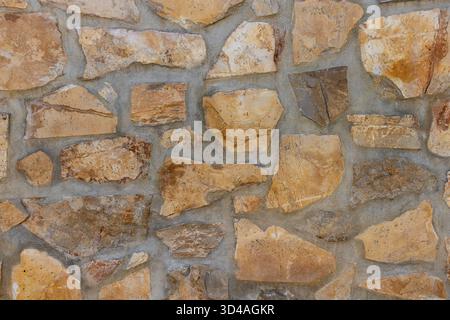 Irregularly shaped natural stones in warm earth tones forming a rustic patterned wall, showcasing robust texture and an authentic  architecture Stock Photo