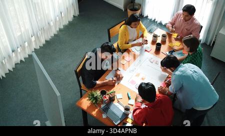 Top down view of diverse people brainstorming and making scrum task board. Group of skilled business team working together and writing sticky notes to Stock Photo