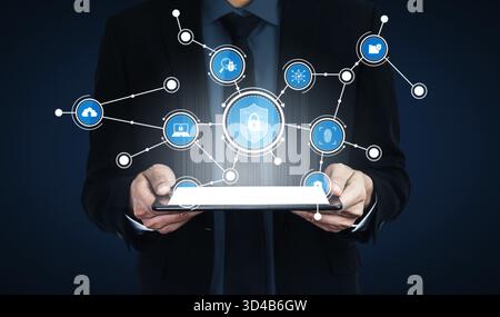A businessman holds a tablet displaying digital icons connected by lines, symbolizing innovation, connectivity, and modern technology in a secure Stock Photo