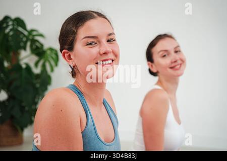 Two cheerful women engage in a delightful yoga session, exuding happiness and serenity as they share smiles and a deep connection through their Stock Photo