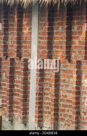 red wall made from hand made bricks with rice thatch above  in the Sundarbans near Kolkata, India Stock Photo