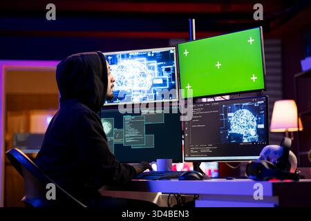 Hacker coding on green screen PC using machine learning to evade security with stealth malware. Evil man using neural network script on mockup computer to hide malicious code from detection systems Stock Photo