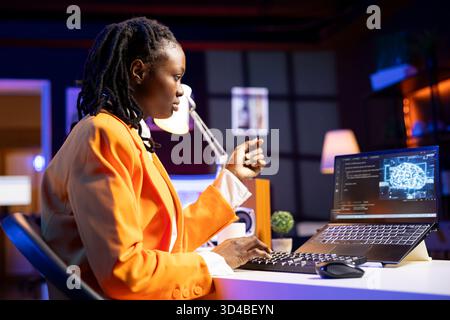 Programmer in living room office typing on keyboard, updating artificial intelligence neural networks, writing binary code scripts. Freelancing system administrator upgrading high tech AI Stock Photo