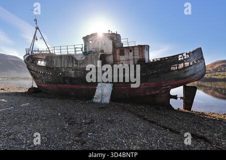 056 Wood fishing boat Golden Harvest shipwreck on the shingle beach at Loch Linnhe N end, Ben Nevis mountain in left background. Fort William-Scotland Stock Photo