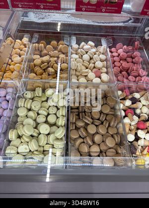 Assorted macarons of various flavors including caramel, pistachio, vanilla, chocolate, and raspberry displayed in clear bins in a dessert shop. Stock Photo